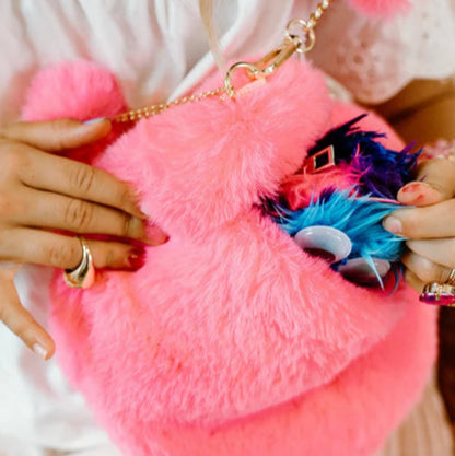 Young girl putting items in her pink furry heart shaped purse form Great Pretenders