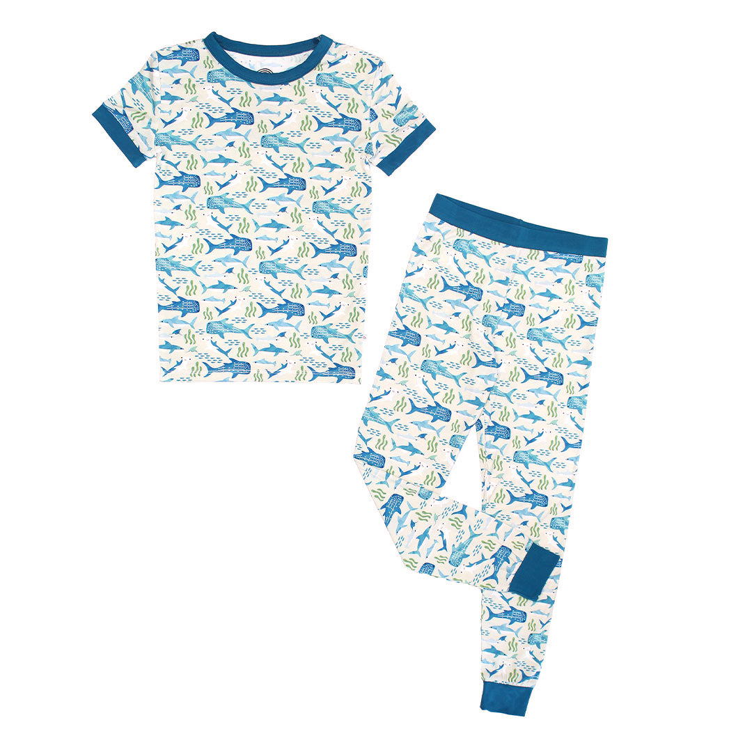 Flat lay picture of our Shark Friends Bamboo Pajama print. The print features a variety of sharks, seaweed beds, and schools of fish.