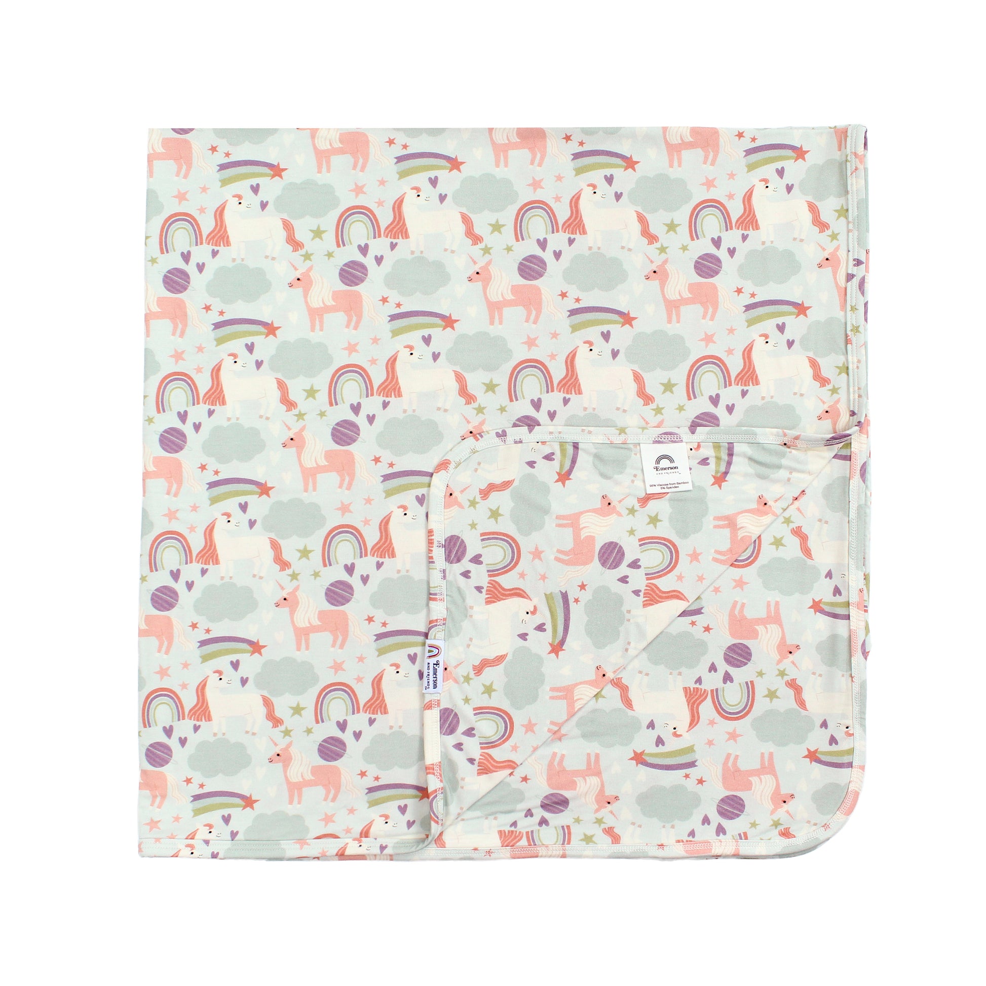 Flat lay picturing our Magical Unicorn Luxury Bamboo blanket on a white background. The print includes unicorns, rainbows, clouds, planets, stars, and hearts. The colors are purple, pink, and blu, with hints of green. 