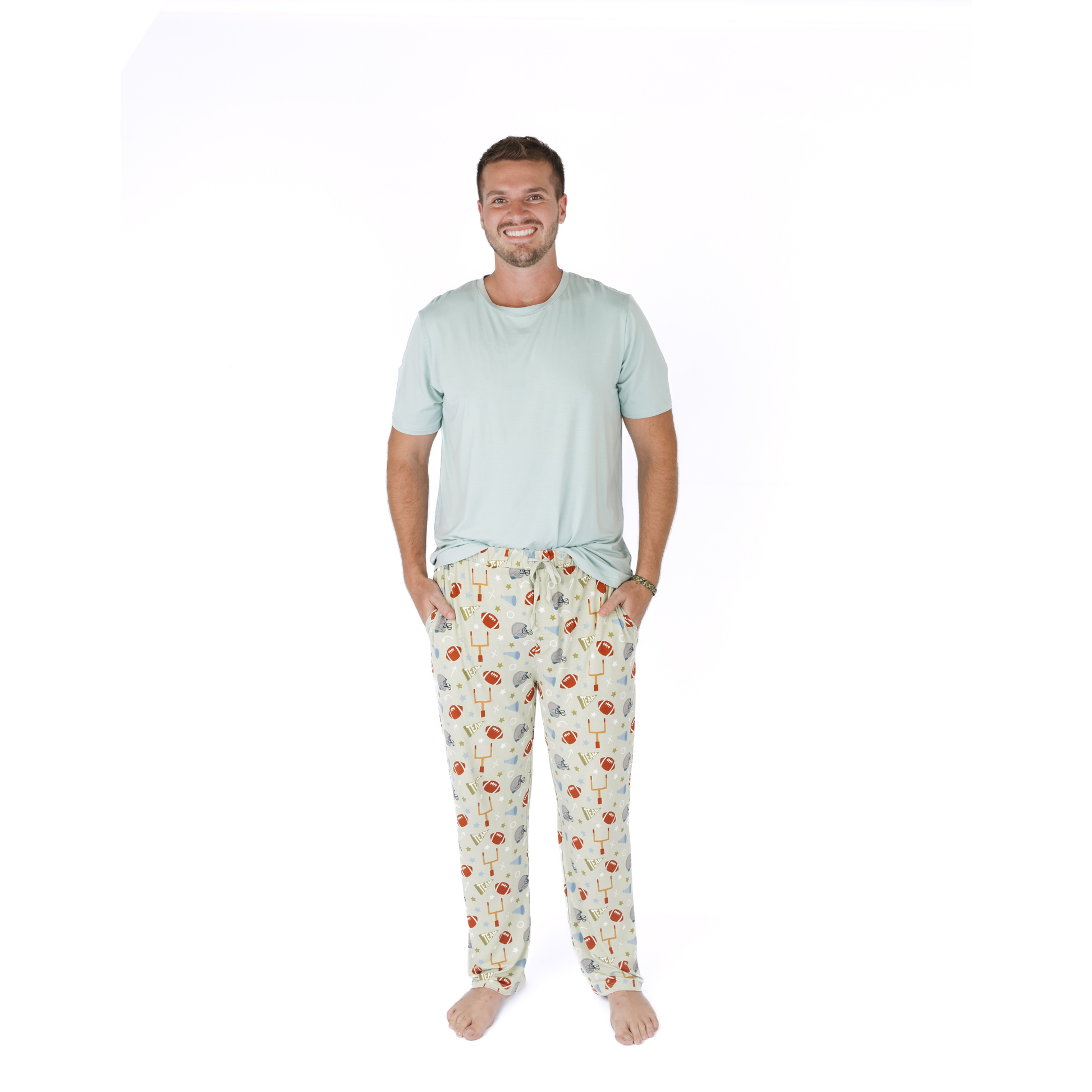 Man wearing a light blue t-shirt and patterned pajama pants on a white background