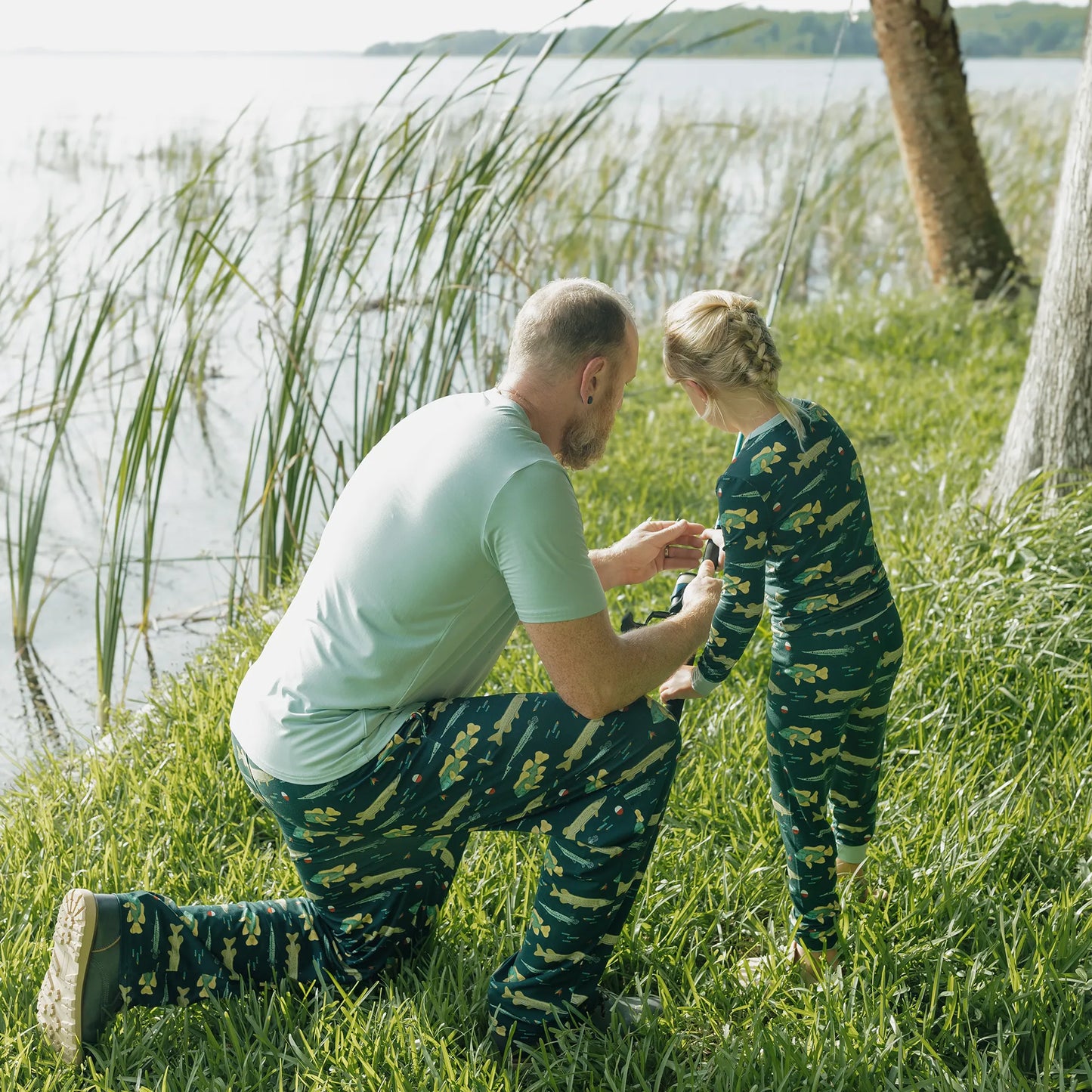 man wearing fish print pants with girl wearing fish print pajama set on greenery background. 