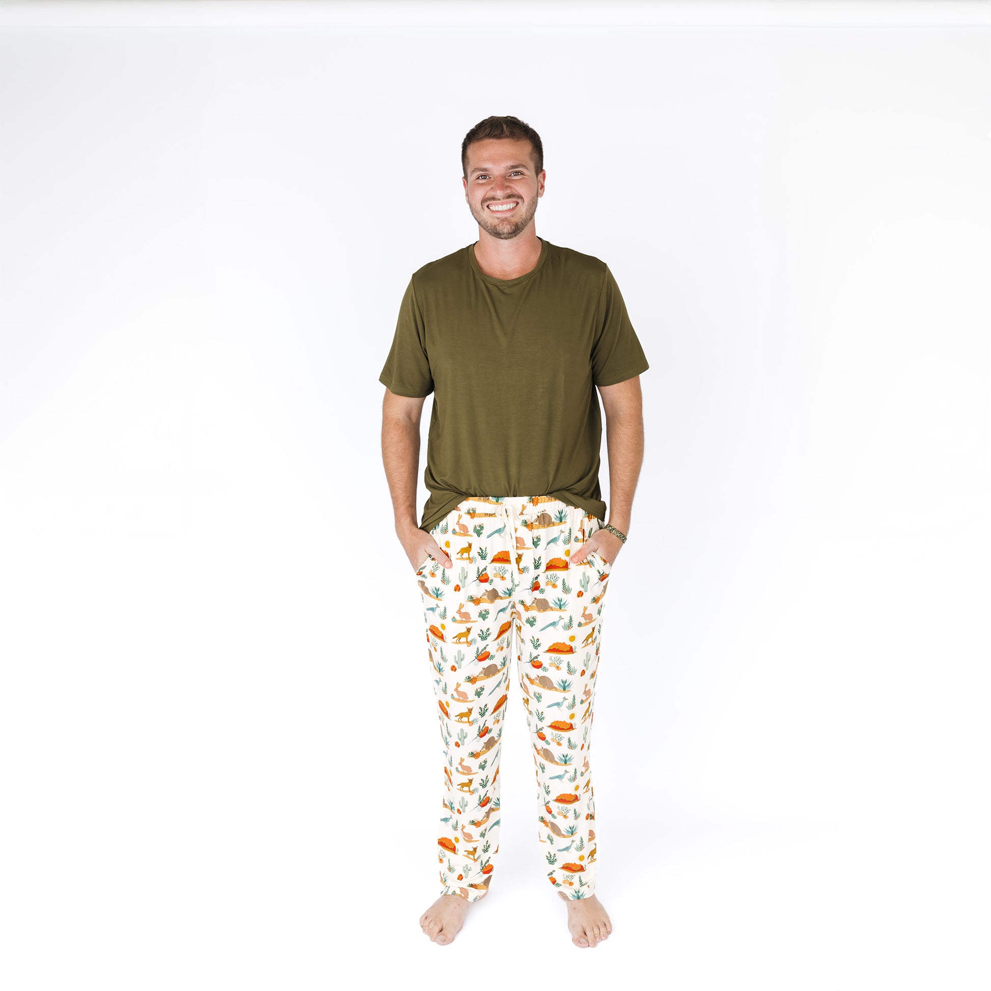 Man wearing a green shirt and patterned pants on a white background