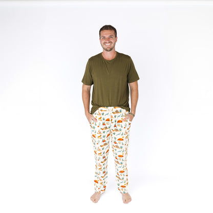 Man wearing a green shirt and patterned pants on a white background