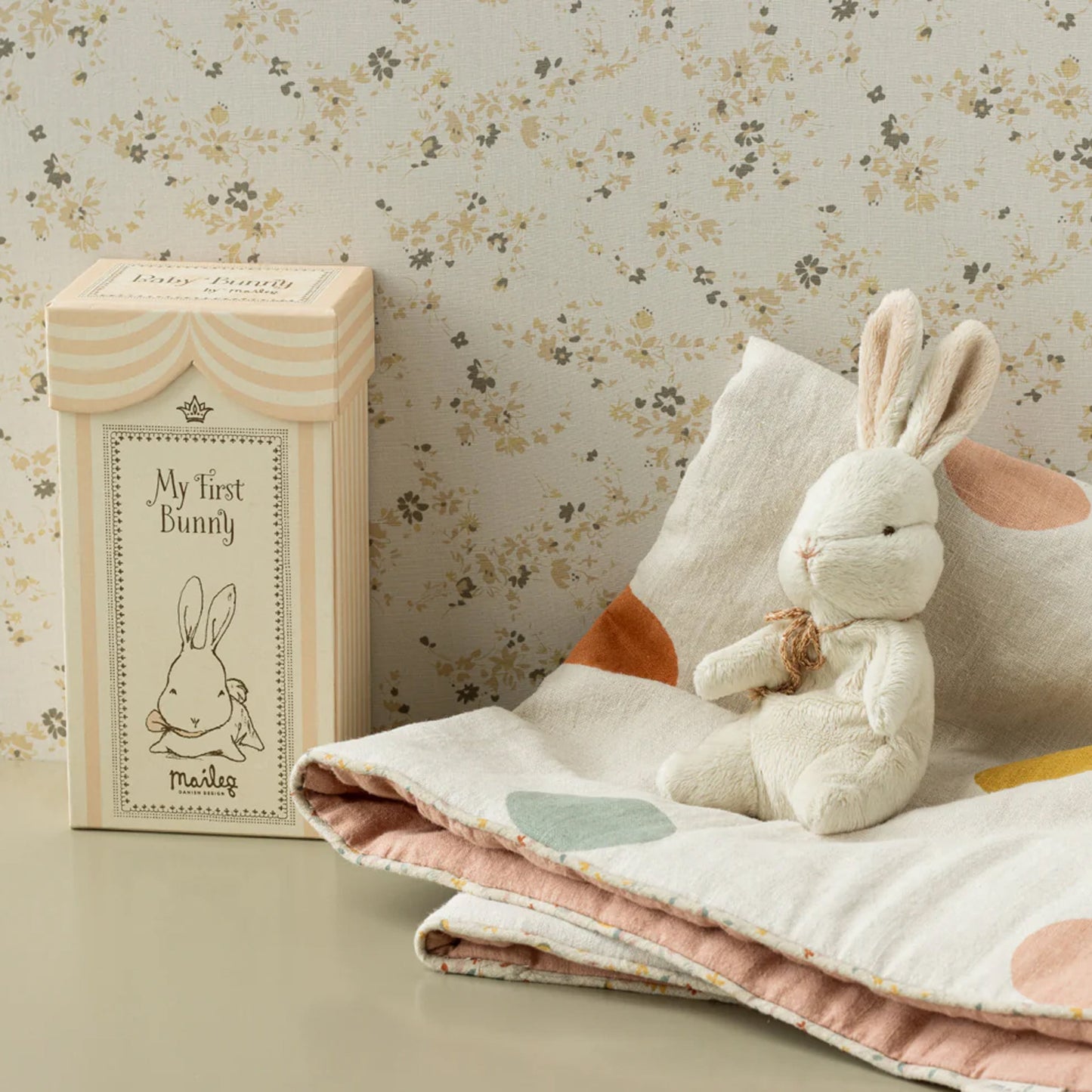 Stuffed bunny toy with packaging on a floral background