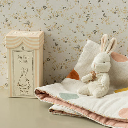 Stuffed bunny toy with packaging on a floral background
