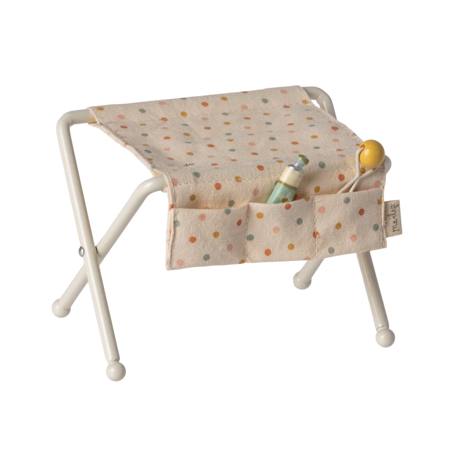 Small stool with a polka dot cushion and a toy on a white background