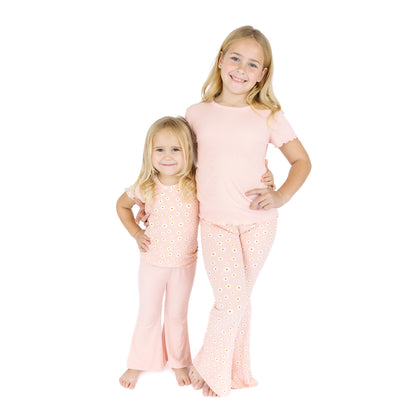 Two children wearing matching pink pajamas with a white background