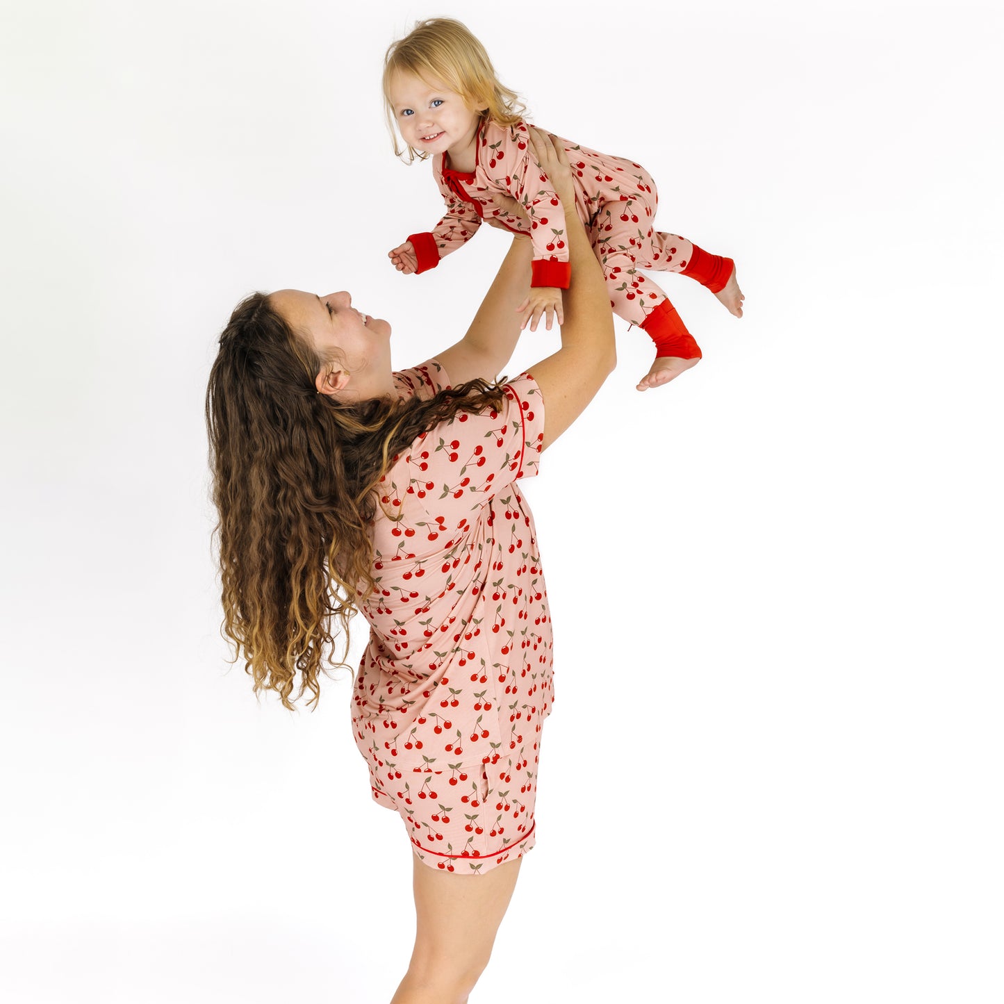 Woman and child wearing matching pajama sets with red hearts on a white background