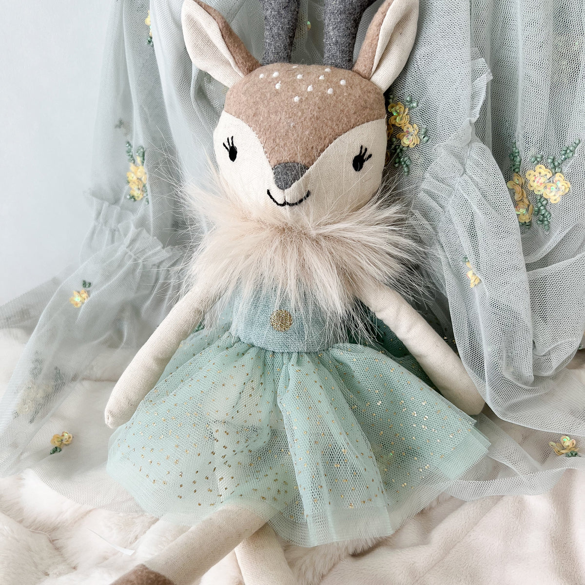 Stuffed deer doll with a light blue dress on a soft background