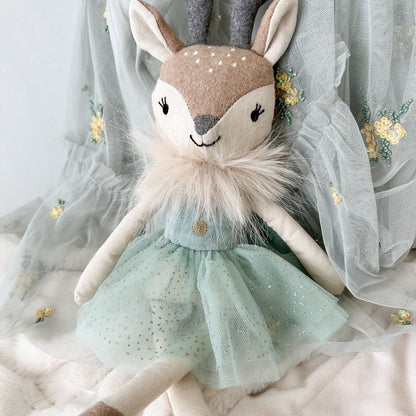 Stuffed deer doll with a light blue dress on a soft background