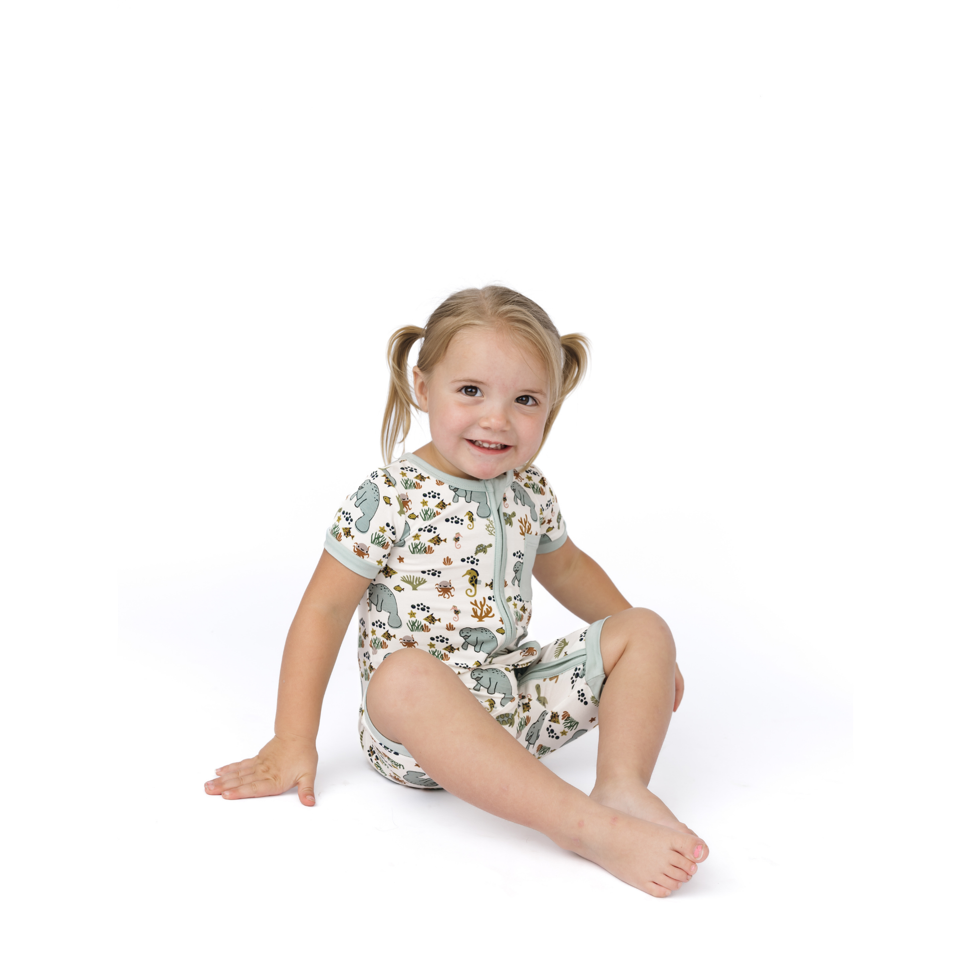 Child wearing a manatee patterned onesie on a white background