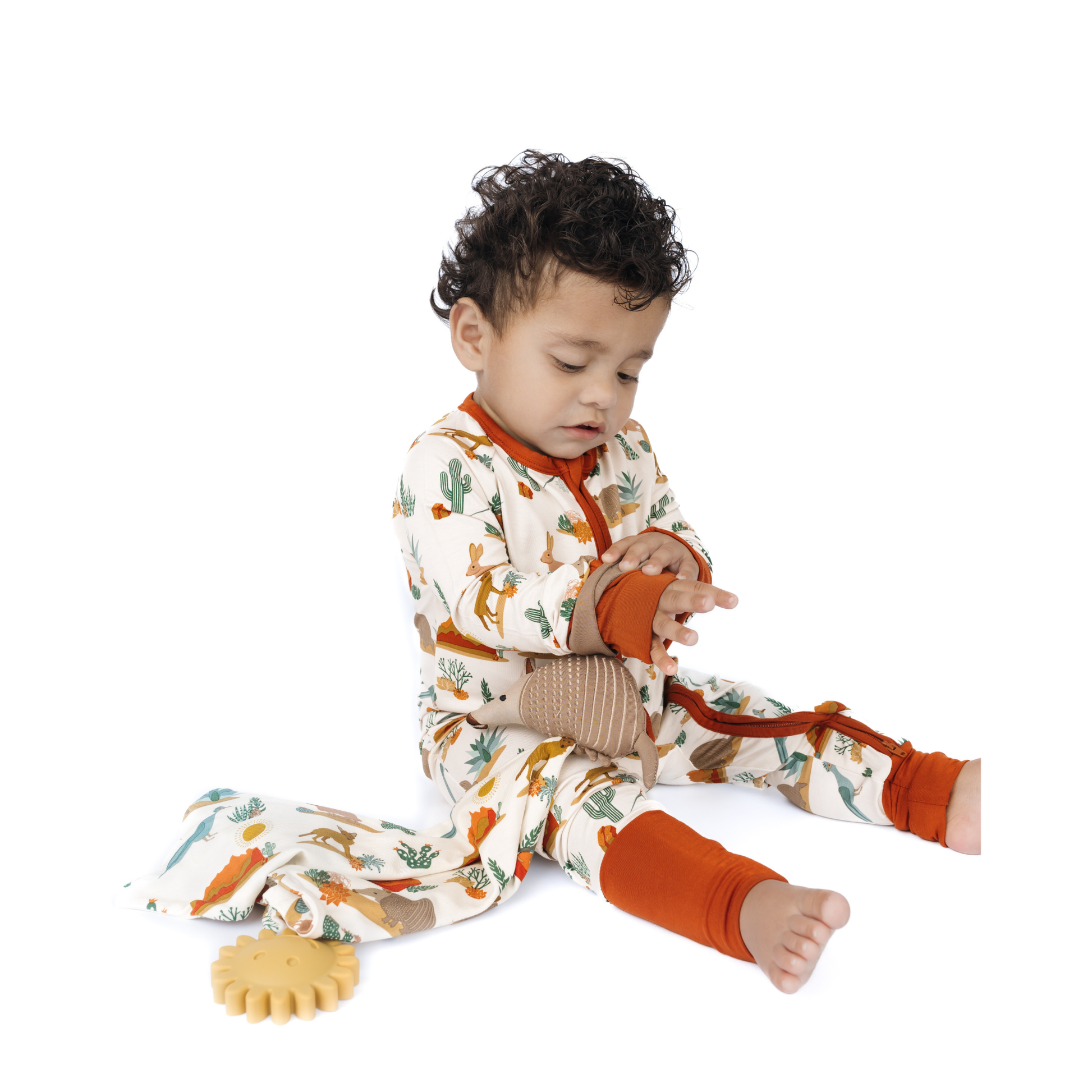 Child wearing a patterned onesie with orange accents on a white background
