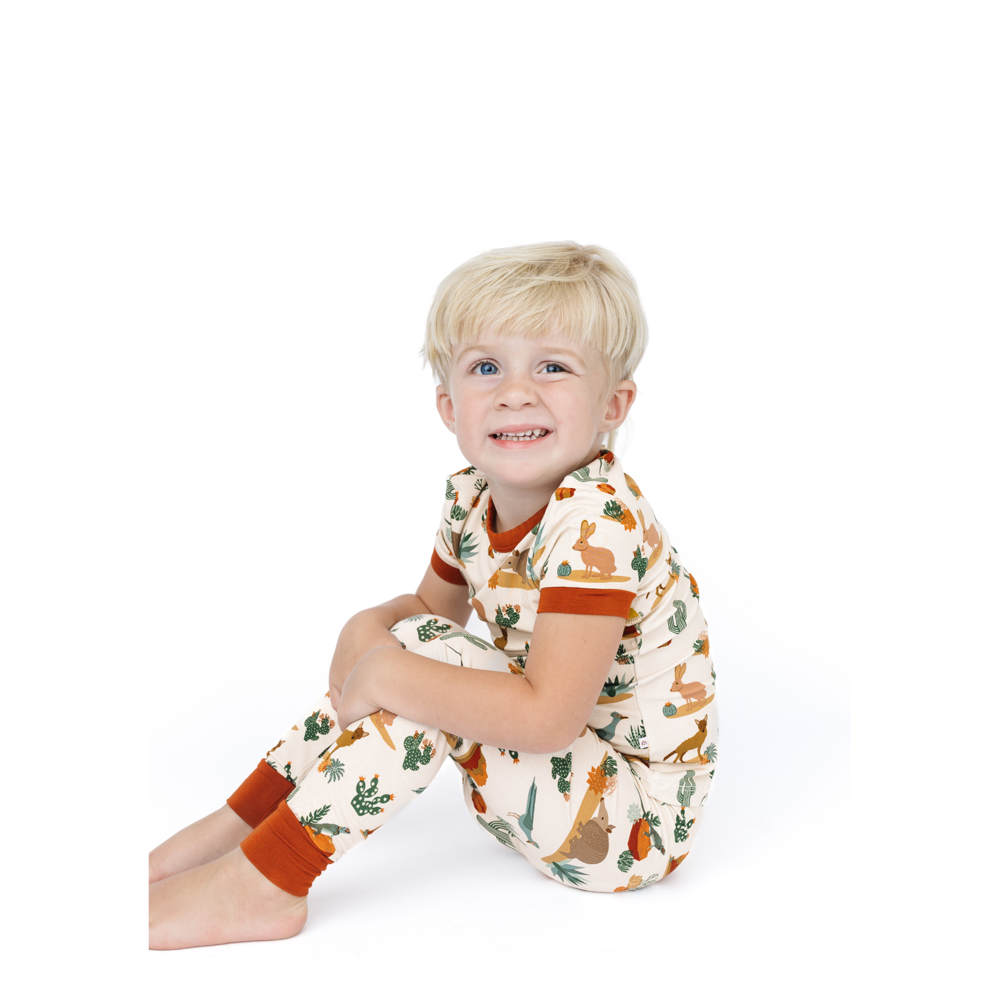 Child wearing a patterned outfit sitting on a white background