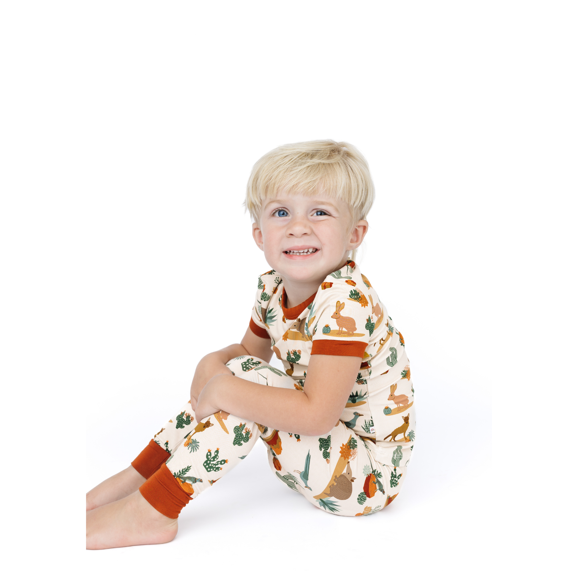 Child wearing a patterned outfit sitting on a white background