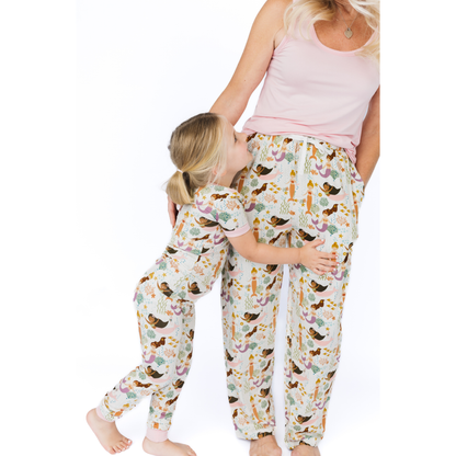 Two people wearing matching pajama pants with a mermaid pattern on a white background