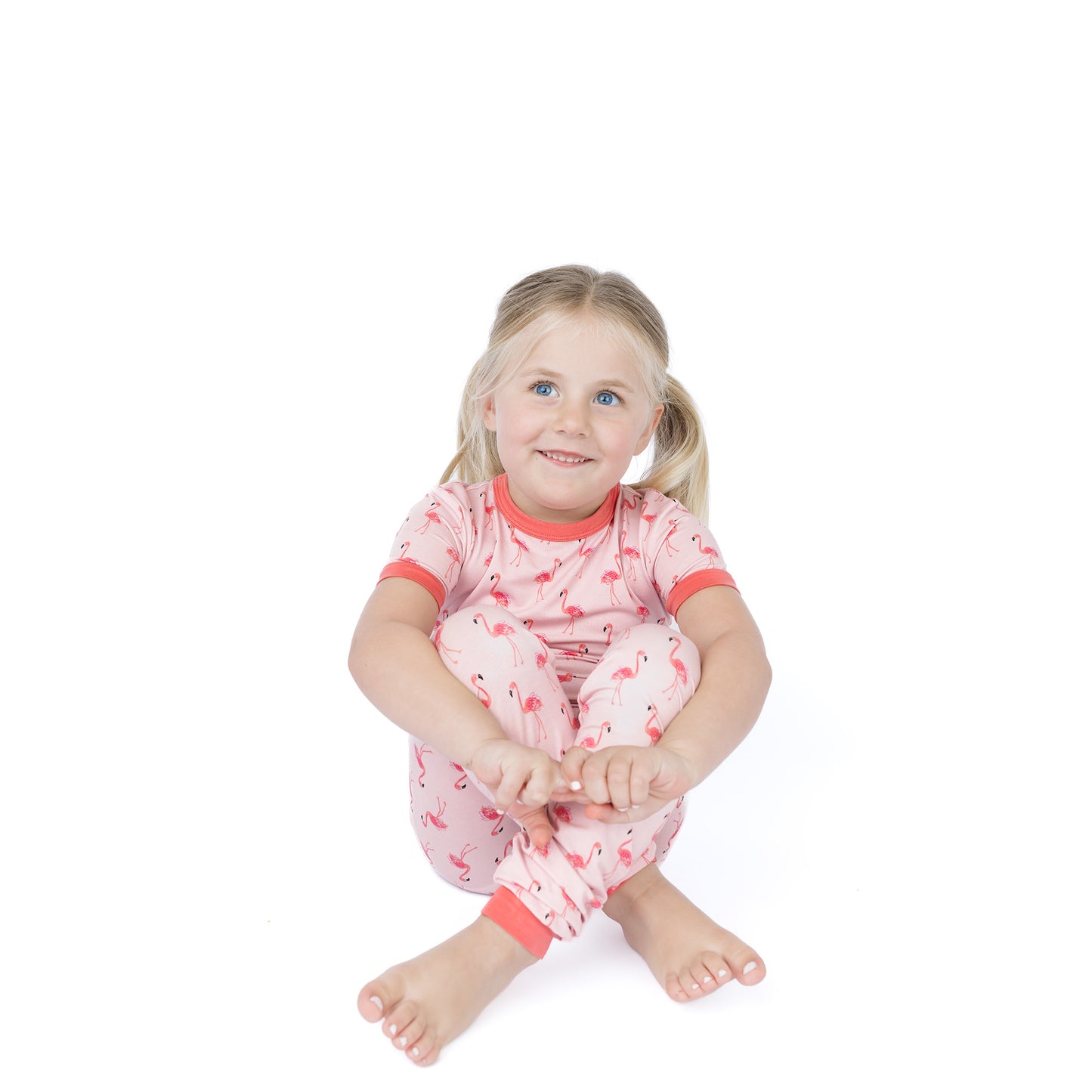 Young girl wearing pink pajamas with flamingo accents on a white background