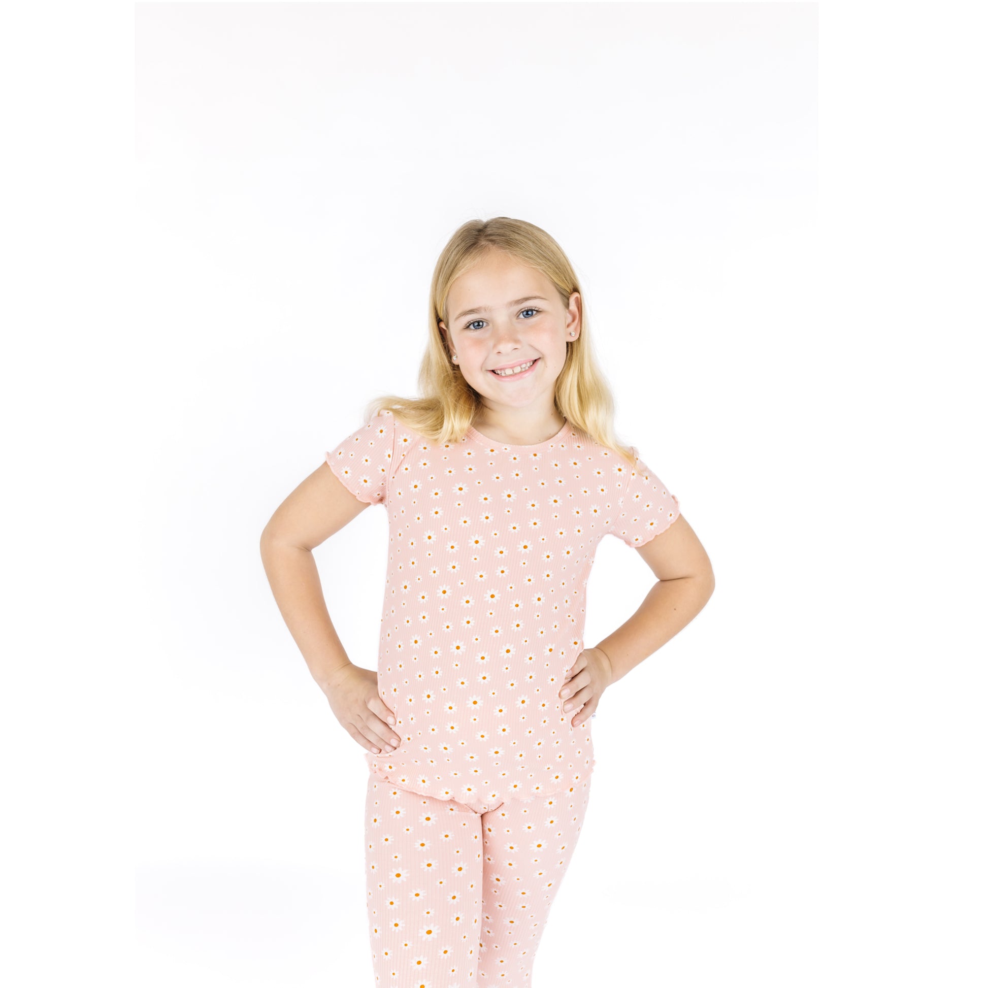 Young girl wearing a pink polka dot pajama set on a white background