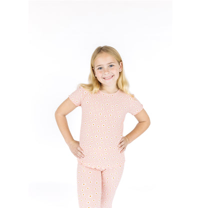 Young girl wearing a pink polka dot pajama set on a white background
