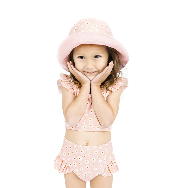 Young girl wearing a pink outfit with matching hat on a white background