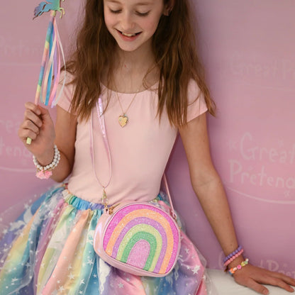 Girl holding a wand carrying the rainbow shaped crossbody purse