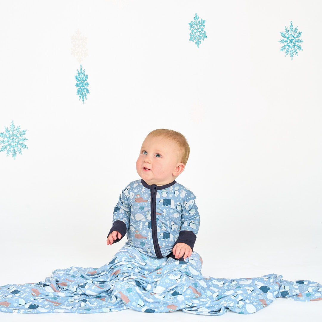 Baby sitting in white background with polar pals pajamas convertible featuring polar bears and blanket