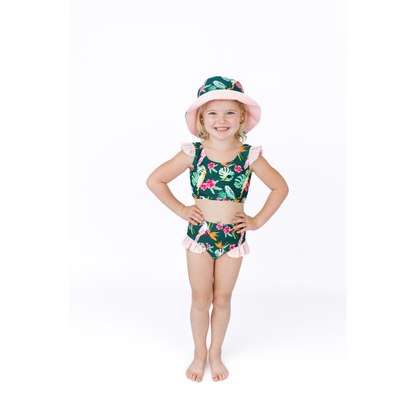 Young girl wearing a floral swimsuit and hat on a white background