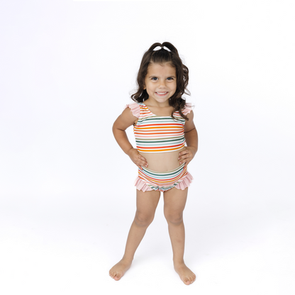 Young girl wearing a colorful striped swimsuit on a white background