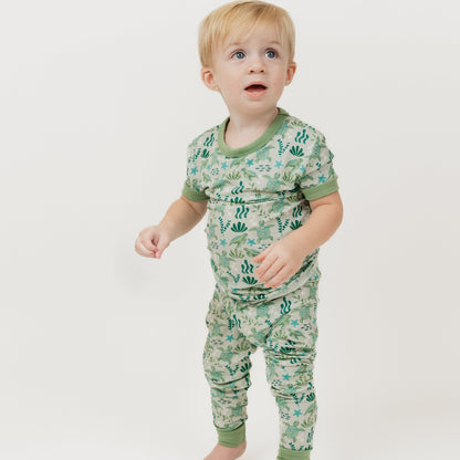 Toddler wearing our Save the Sea Turtles bamboo short sleeve kids pajama pants set by Emerson and Friends. This ultra-soft, eco-friendly pajama set features an adorable sea turtle and ocean-inspired print, perfect for little nature lovers. Designed for all-night comfort with breathable bamboo fabric.