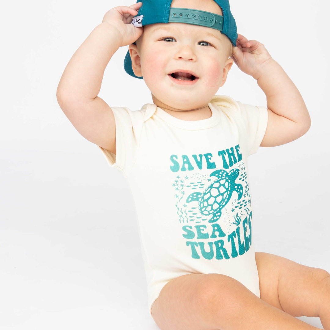 Baby wearing our Save the Sea Turtle  onesie made of 100% cotton by Emerson and Friends. He also have our Save the Sea Turtle hat. 
