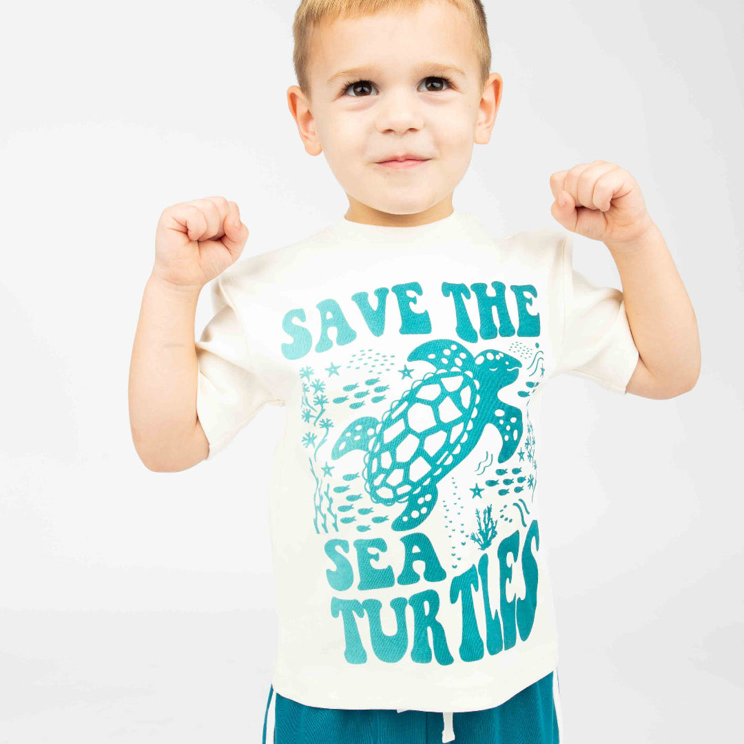 A boy wearing our Save the Sea Turtle tee in a white background. 