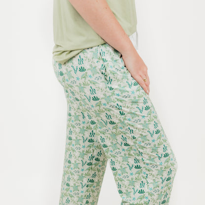 Woman wearing our Relaxed Long Pants from our Save the Sea Turtle Collection. Featuring\a serene ocean-inspired print with sea turtles and marine life, these ultra-soft bamboo pieces are breathable, moisture-wicking, and eco-friendly. Perfect for lounging or sleeping in sustainable style.