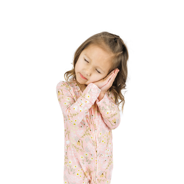 Young girl wearing a pink floral onesie on a white background