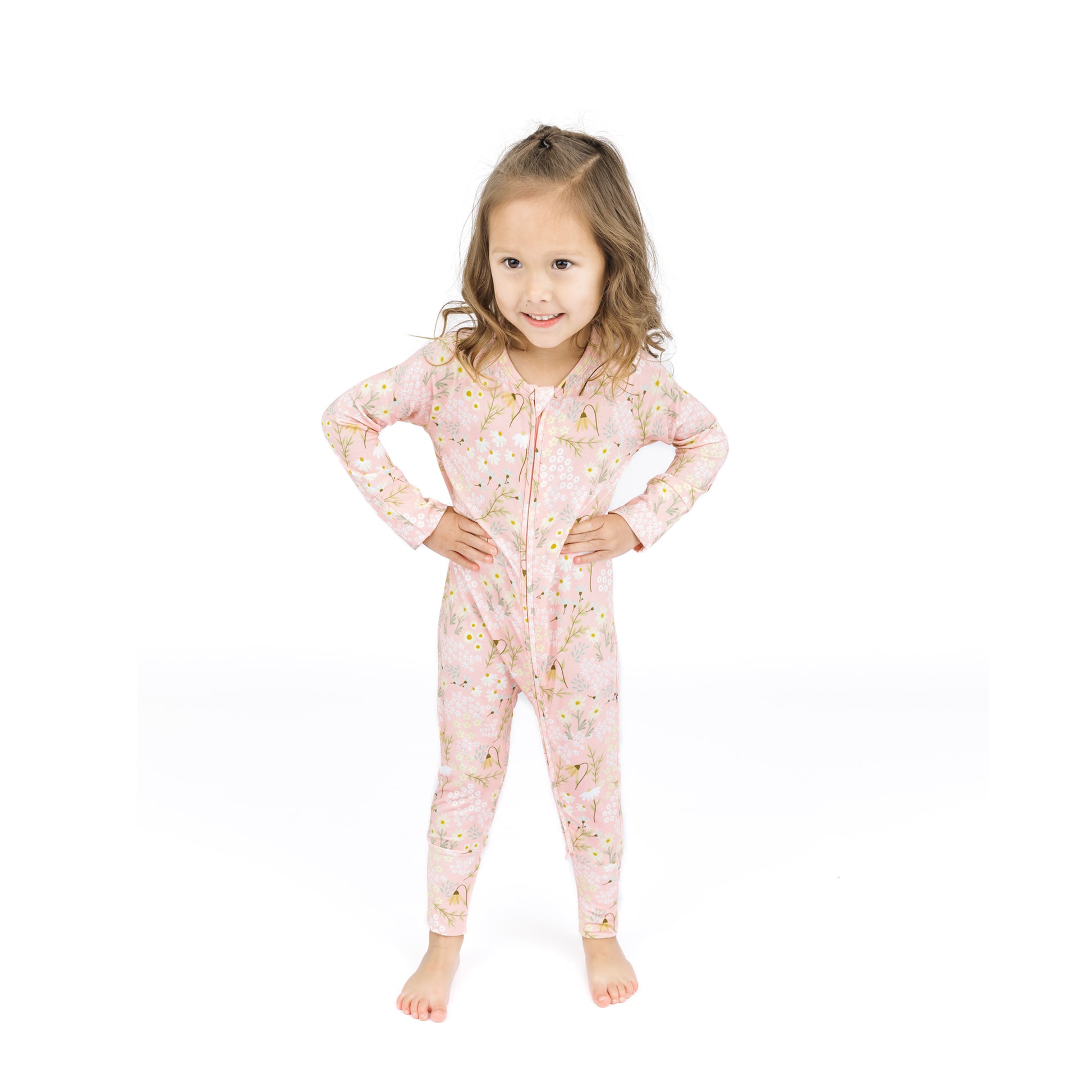 Young girl wearing a pink floral onesie on a white background