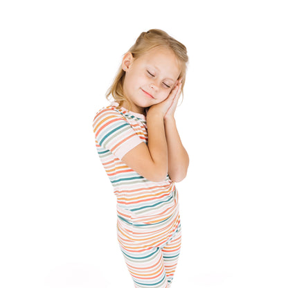 Young girl wearing a colorful striped outfit on a white background