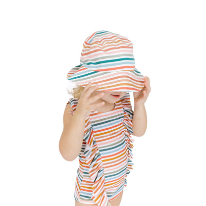 Child wearing a colorful striped hat and dress on a white background