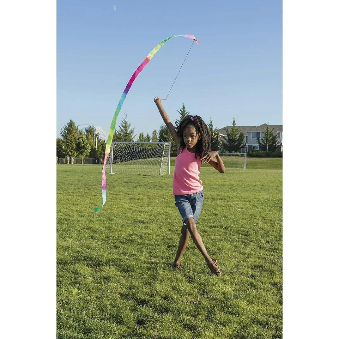 Child playing a colorful stunt ribbon in a park on a clear day