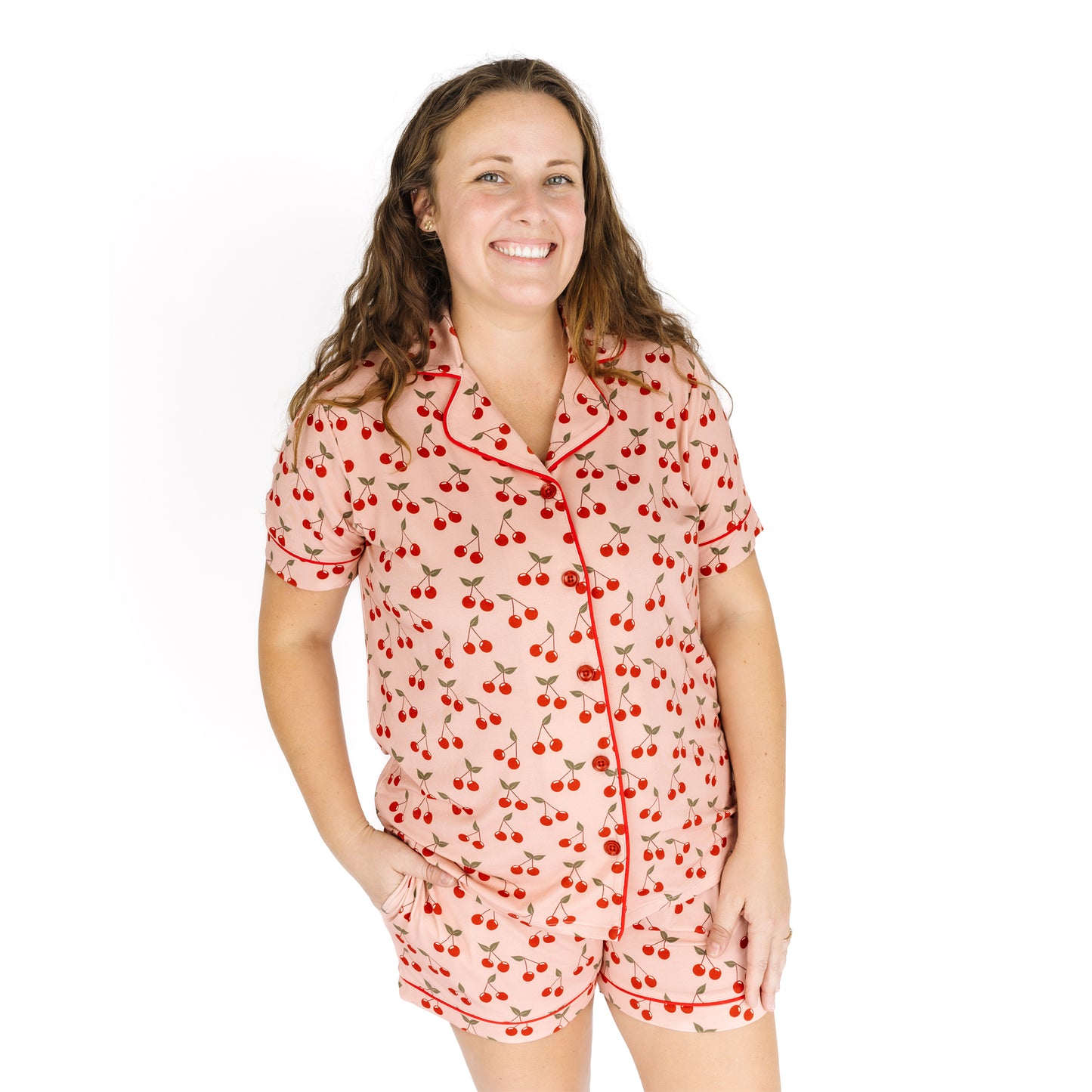 Woman wearing a cherry-patterned pajama set on a white background