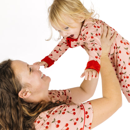 Woman and child wearing matching cherry-patterned outfits on a white background