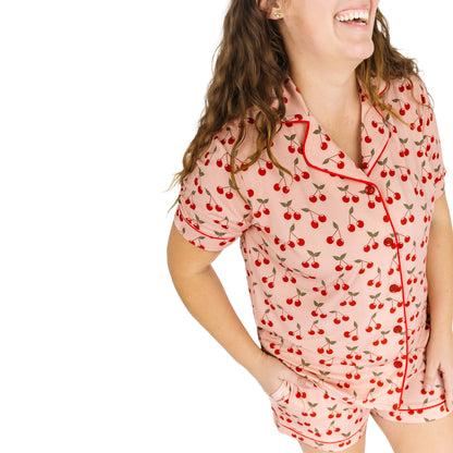 Woman wearing a cherry-patterned pajama set on a white background