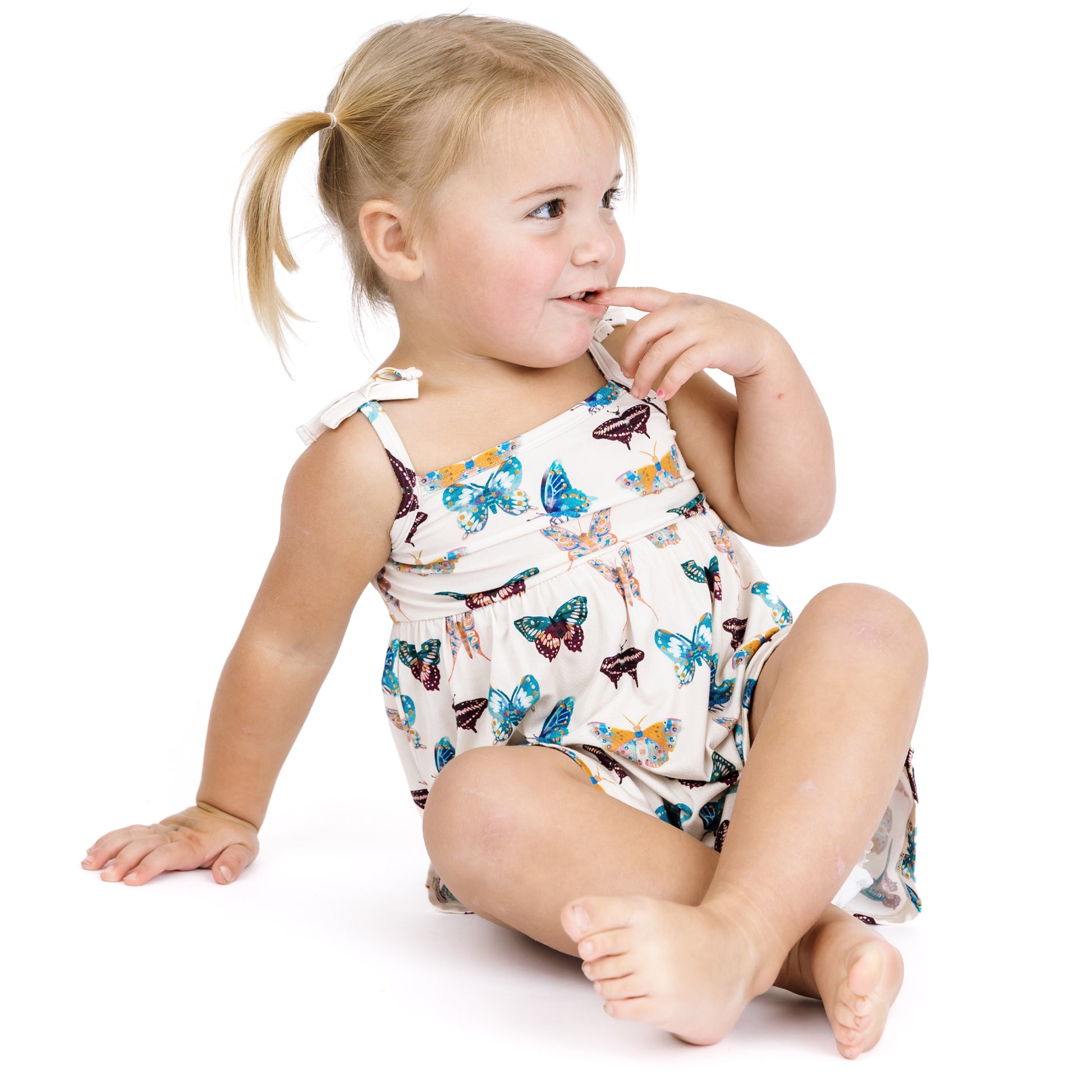 Child wearing a butterfly-patterned romper on a white background