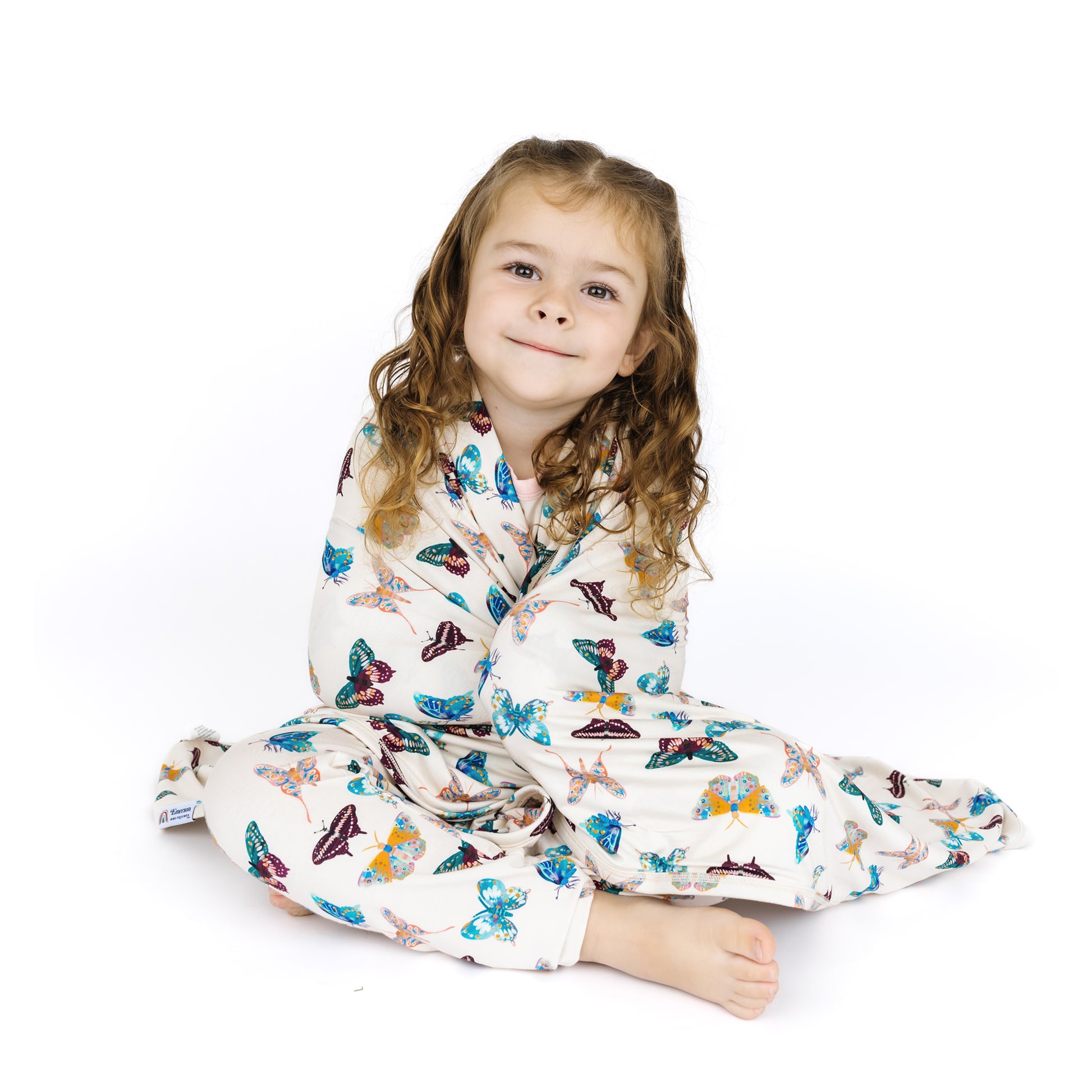 Child wearing a butterfly-patterned pajama with matching blanket on a white background