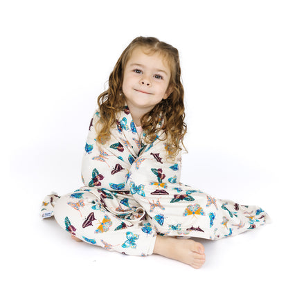 Child wearing a butterfly-patterned pajama with matching blanket on a white background