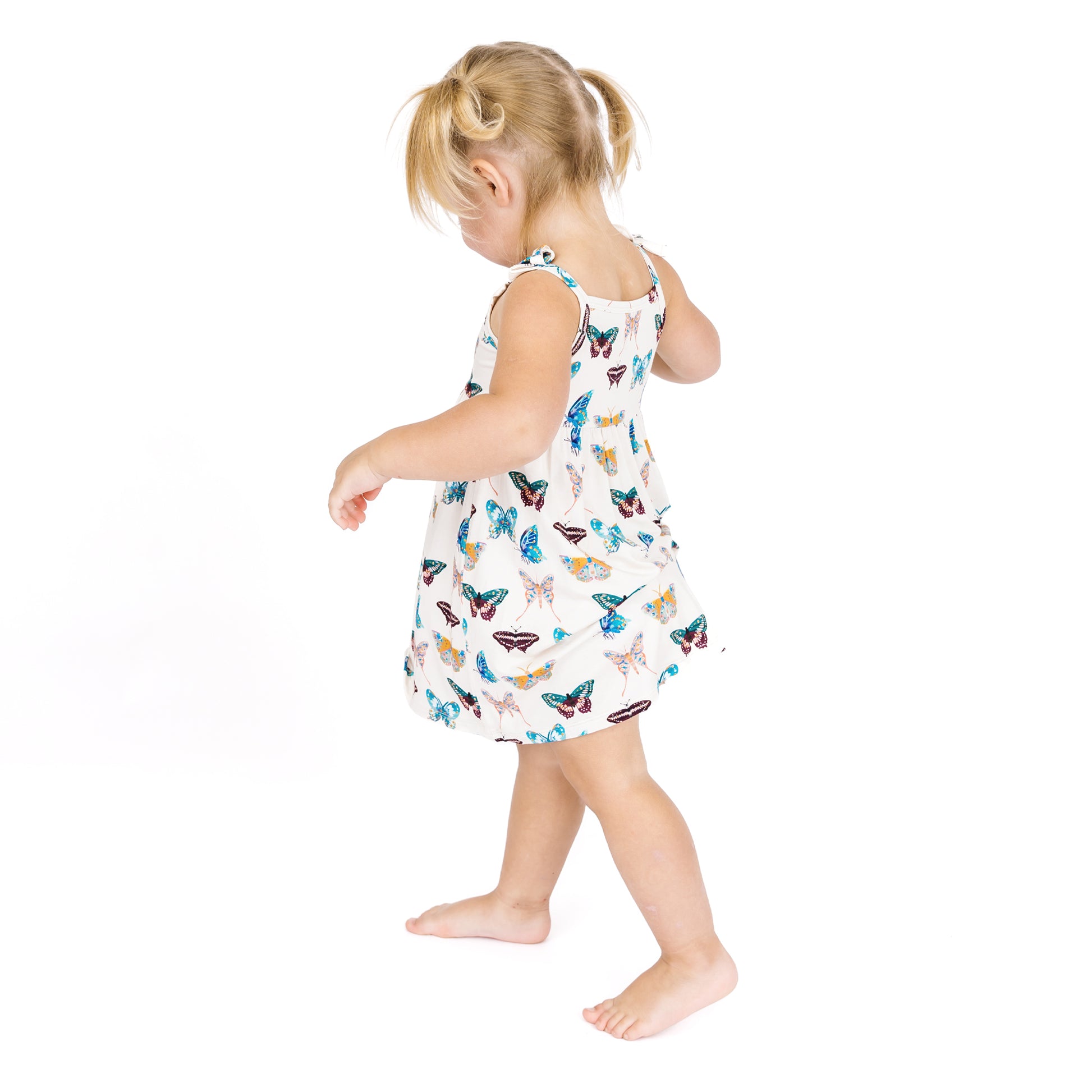 Child wearing a dress with butterfly pattern on a white background