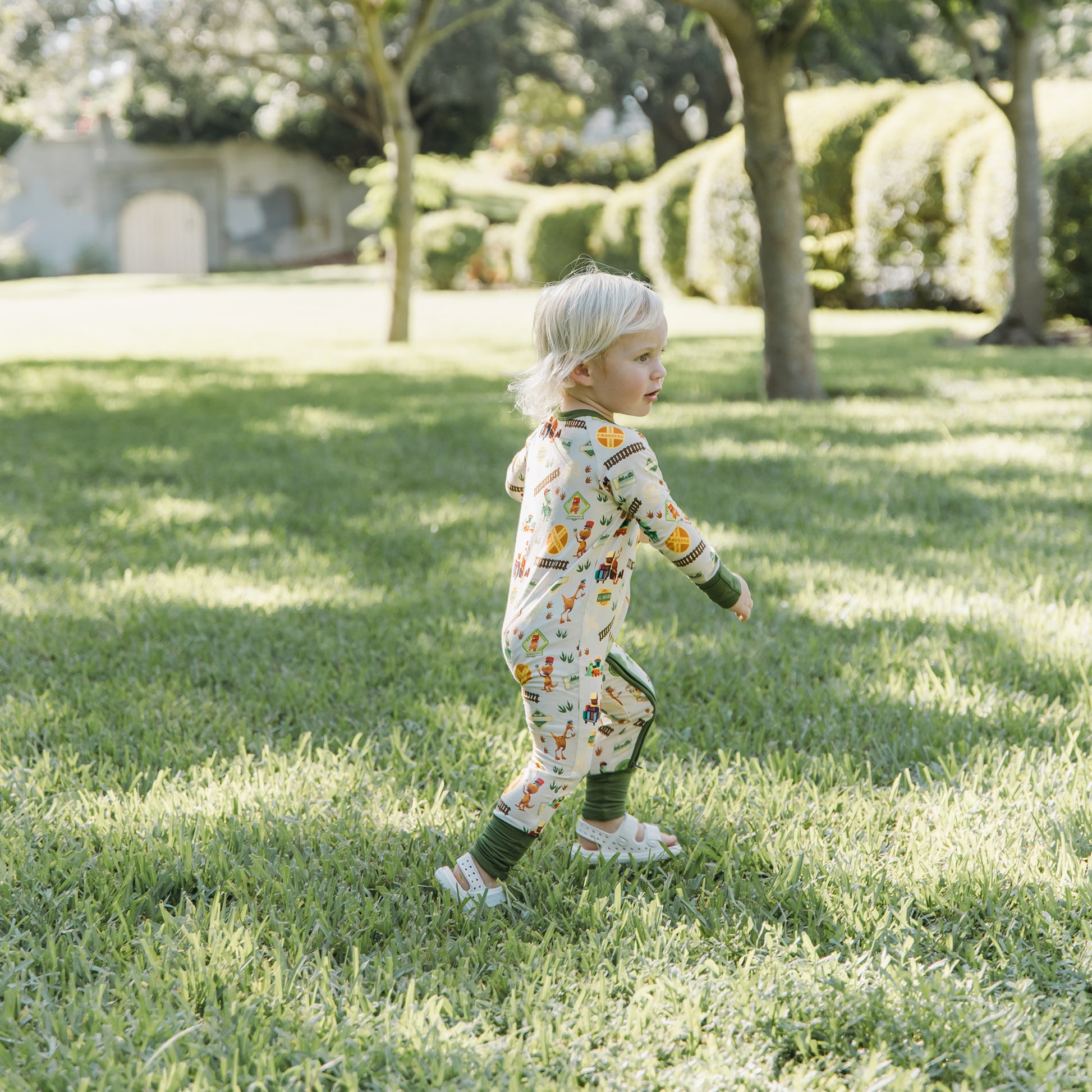 Toddler walking in the park wearing All Aboard the Dinosaur Train™ bamboo pajamas
