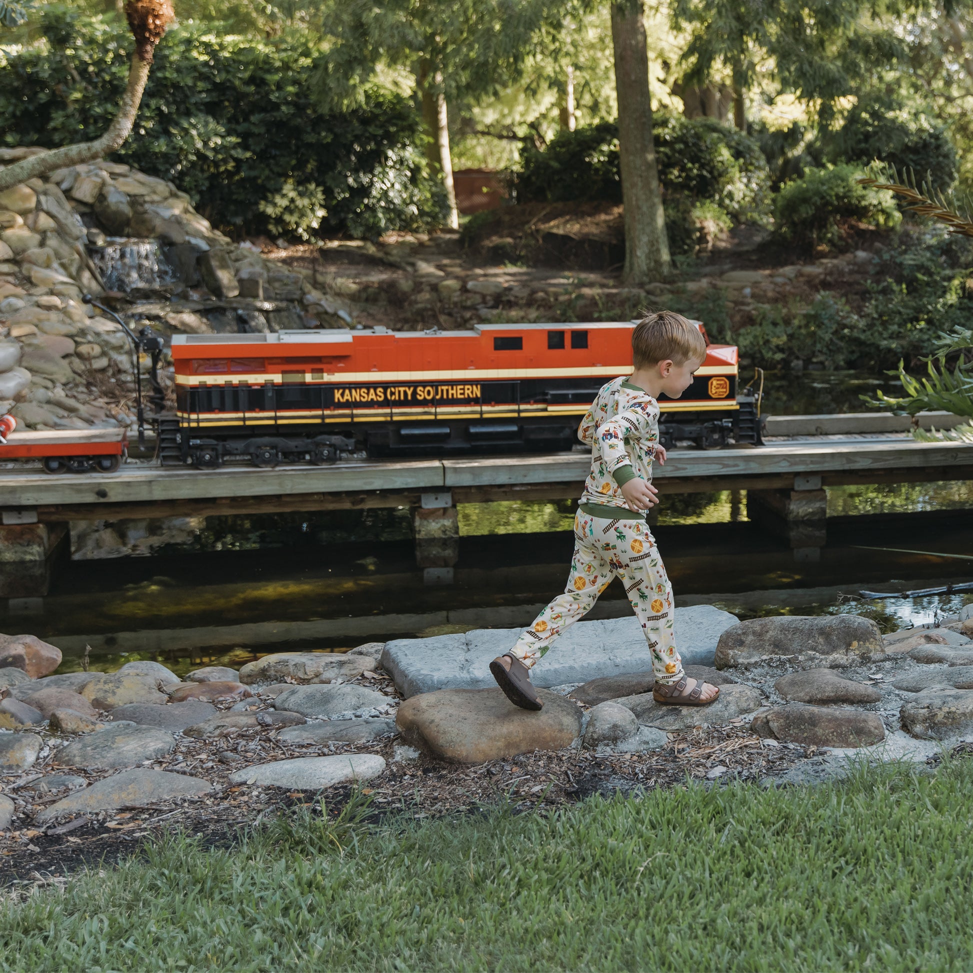 Toddler wearing All Aboard the Dinosaur Train™ bamboo pajamas playing outdoors.
