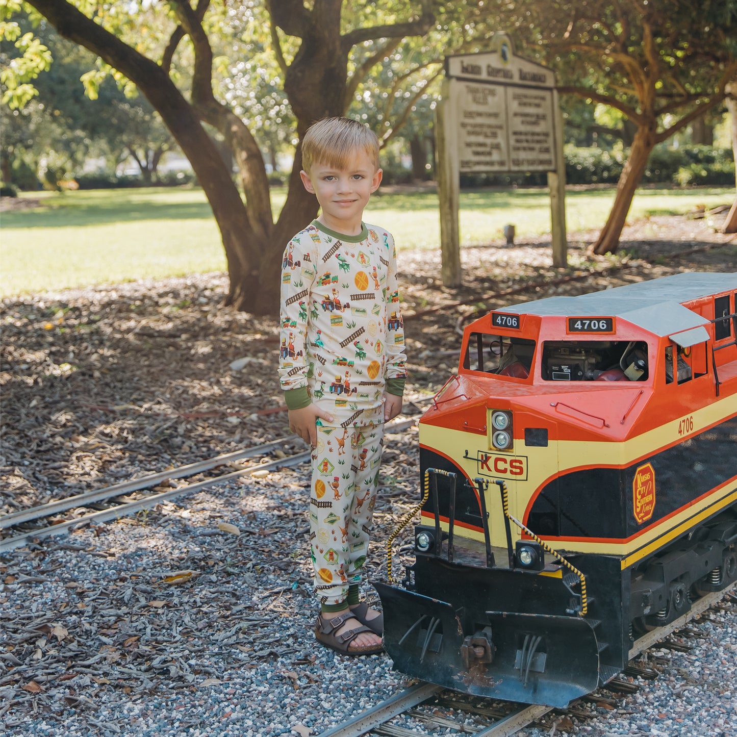 Child in All Aboard the Dinosaur Train™ bamboo pajamas watching a model train pass