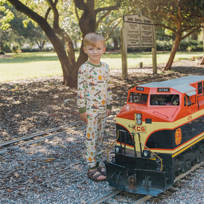 Child in All Aboard the Dinosaur Train™ bamboo pajamas watching a model train pass
