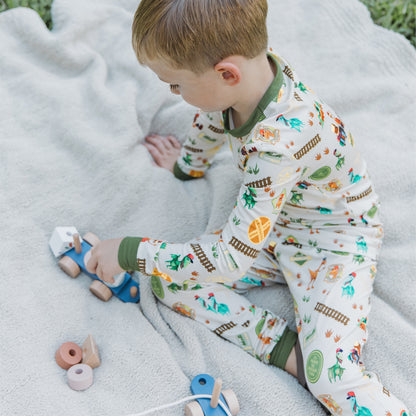 Toddler wearing All Aboard the Dinosaur Train™ bamboo pajamas playing in the blanket. 