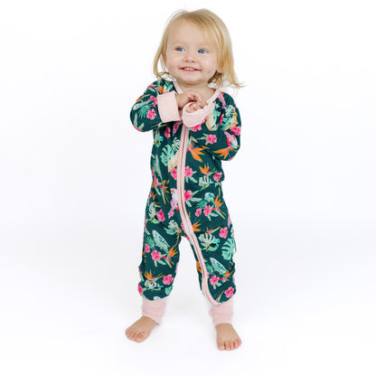 Baby standing while wearing the Isla Botánica tropical birds print bamboo romper, showing the comfortable and stretchy fit.