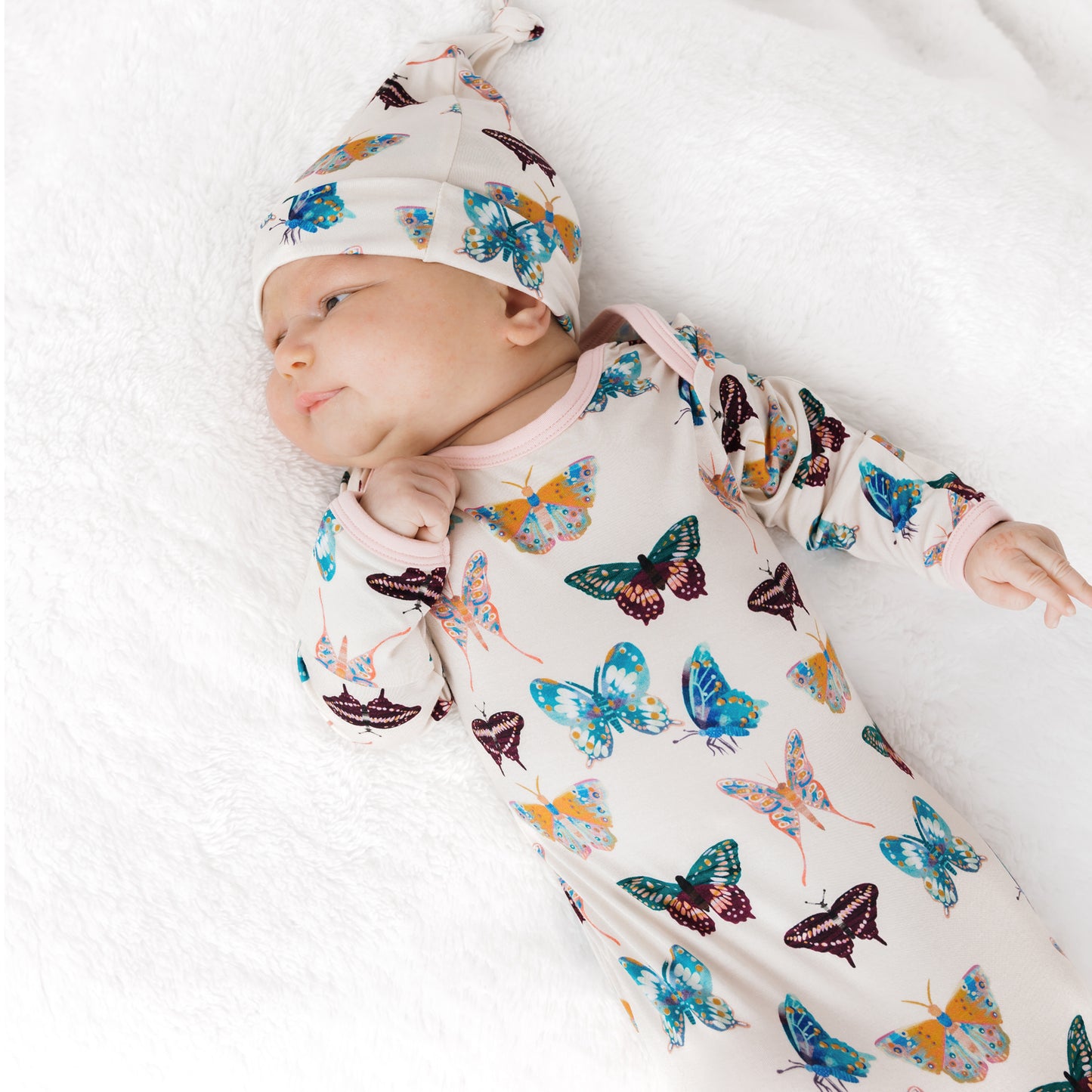 Snugly newborn baby wearing the soft Wings of Paradise butterfly print bamboo gown and hat.